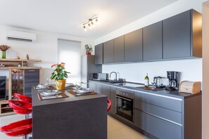 A modern kitchen with grey cabinets, a central island, and a microwave. - Premium beachfront apartment (Banjole)