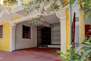 A courtyard with a yellow wall, a black gate, and a red door. - Classic Zamindar Heritage (Puducherry)