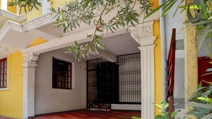 A courtyard with a yellow wall, a black gate, and a red door. - Classic Zamindar Heritage (Puducherry)