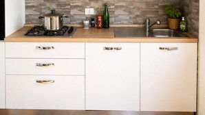 Moderni keittiö, jossa on puukuvioiset kaapit, kaasuliesi, ruostumattomasta teräksestä valmistettu pesuallas ja kuvioitu välitila.