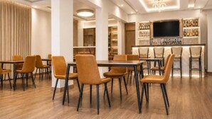 A modern hotel lobby with a bar area, seating arrangements, and a television screen.