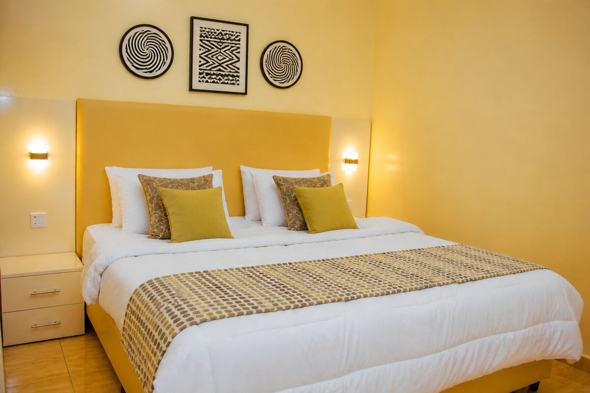 A hotel room with a bed, bedside tables, and wall-mounted light fixtures.