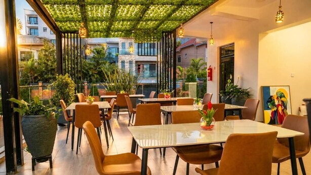A restaurant with outdoor seating, tables, chairs, and potted plants.