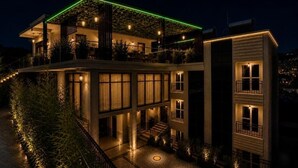 A multi-story building with a rooftop garden, a covered terrace, and a courtyard with a circular pattern.