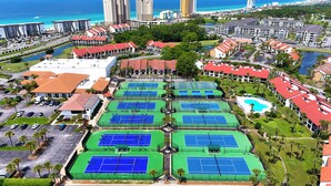 Lomakeskus, jossa on useita tenniskenttää, uima-allas ja näkymä merelle.