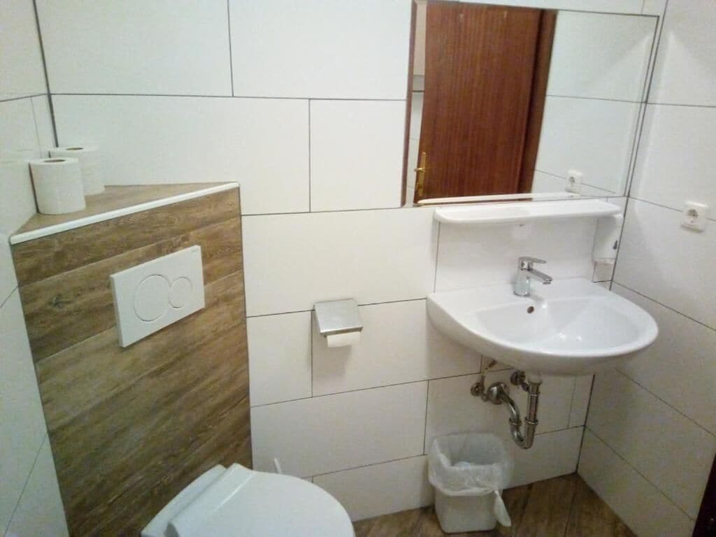 Un baño con lavamanos blanco, inodoro y espejo sobre el lavamanos.