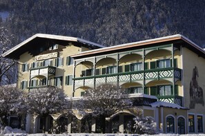 A multi-story building with a balcony on the second floor, surrounded by snow-covered trees.