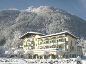 Un hotel de varios pisos con balcones, con montañas al fondo.