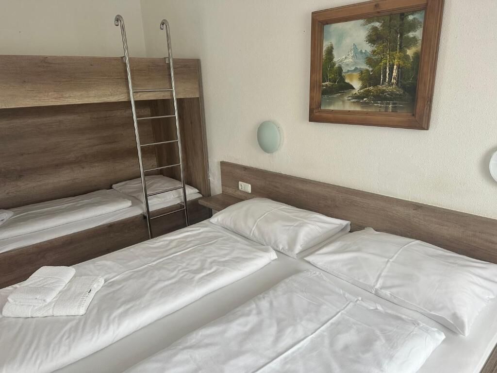 A room with bunk beds, a ladder, a painting, and a bedside table.