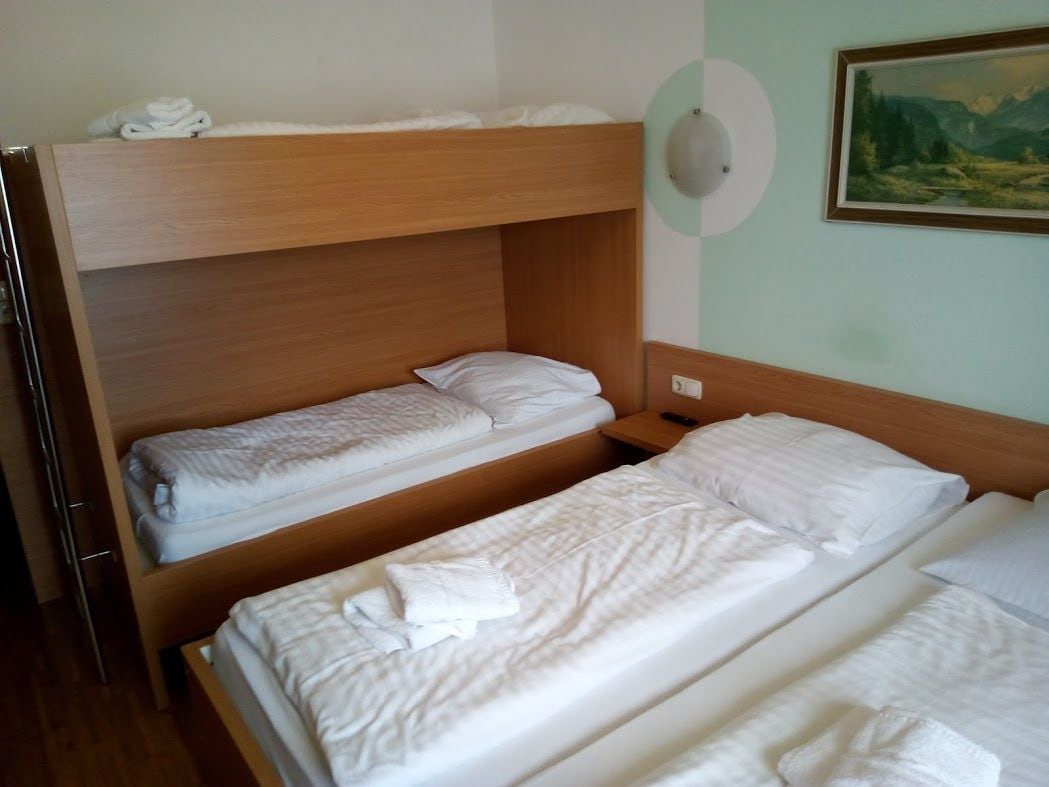 A room with two bunk beds, a painting on the wall, and a light switch.
