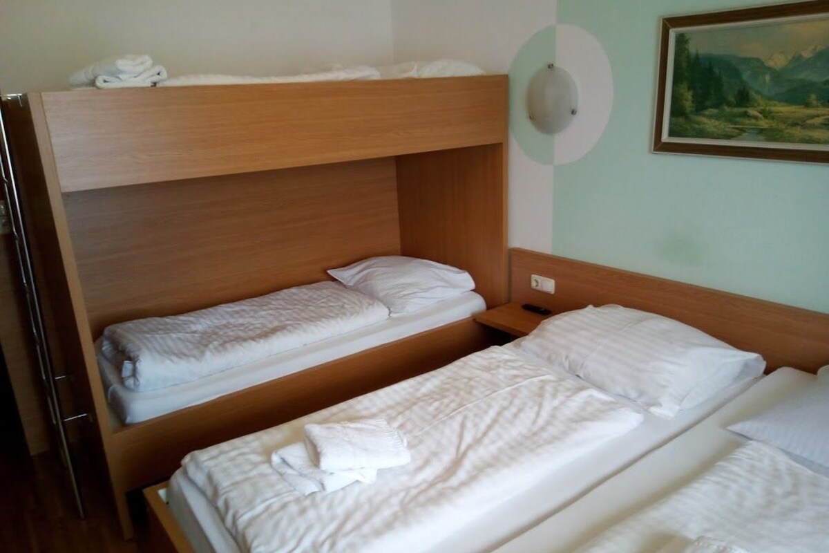A room with two bunk beds, a painting on the wall, and a light switch.