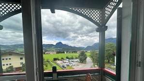 Un balcon donnant sur un paysage verdoyant et des montagnes.