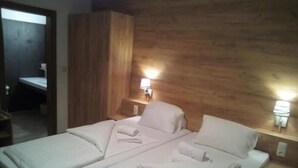 Un lit double avec du linge de lit blanc, deux lampes de chevet et une tête de lit en bois.