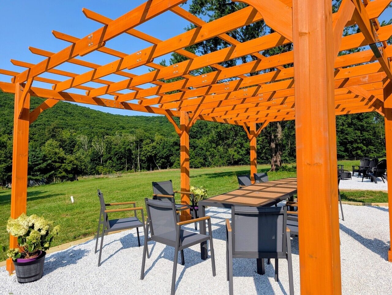An outdoor seating area with a pergola structure, a table, and chairs.