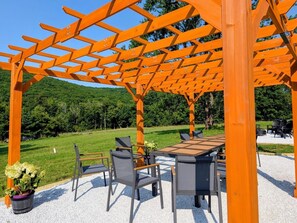 An outdoor seating area with a pergola structure, a table, and chairs.