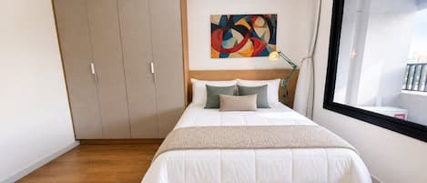 Un dormitorio con cama, un cuadro, una ventana y un armario.