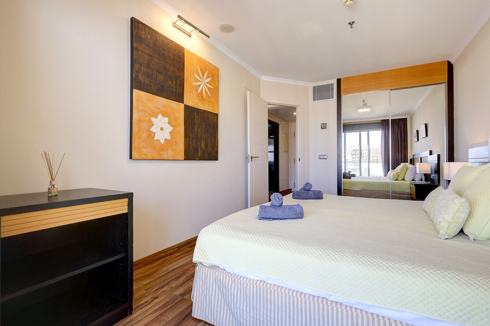 Une chambre d’hôtel avec un grand lit, un bureau, un miroir et une œuvre d’art murale.
