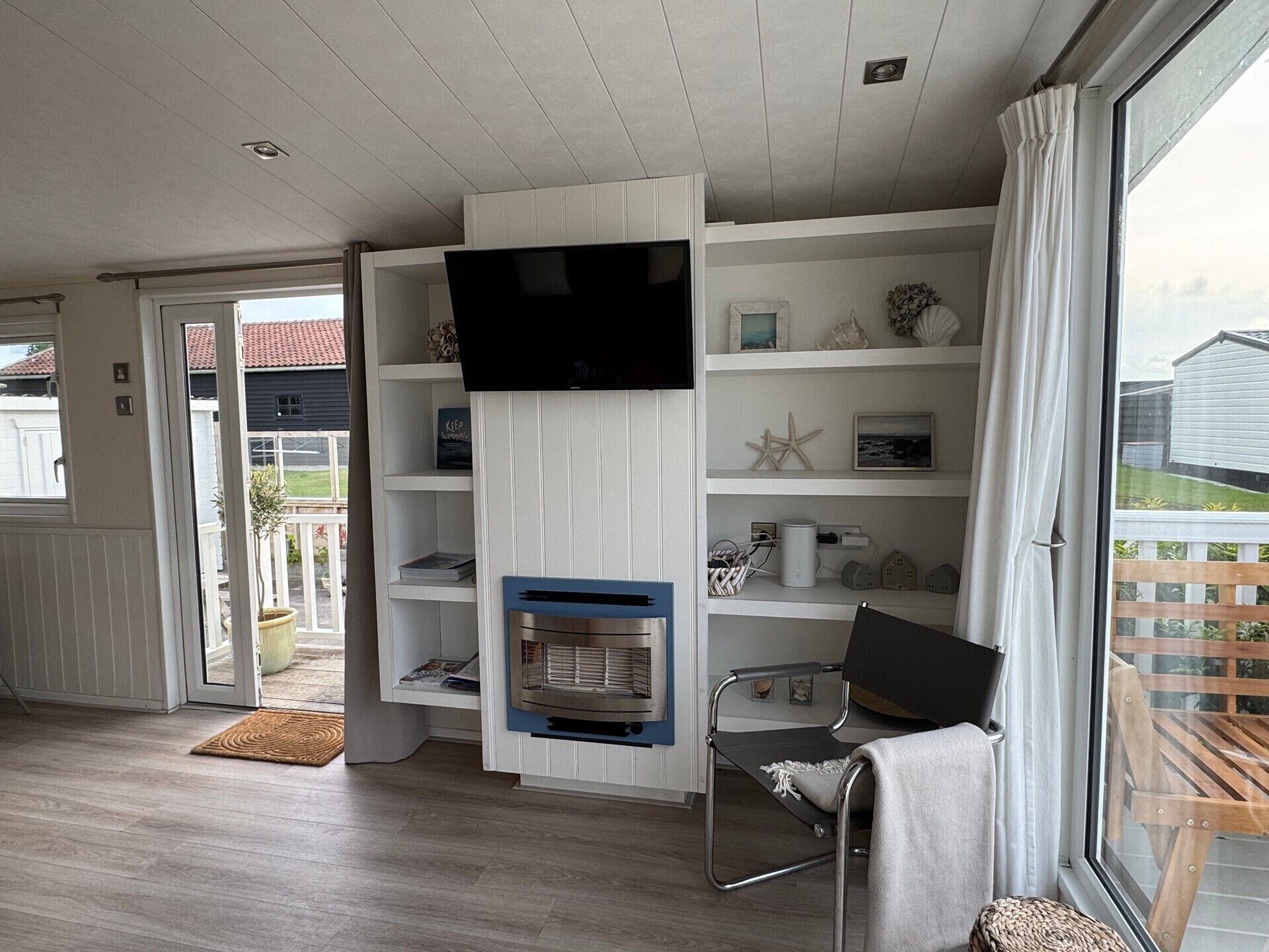 Een kamer met een televisie, een open haard, een stoel en uitzicht op buiten.