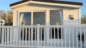 A white mobile home with a fenced deck and large windows. - Camping Zeezicht - Chalet 16 (Westerland)