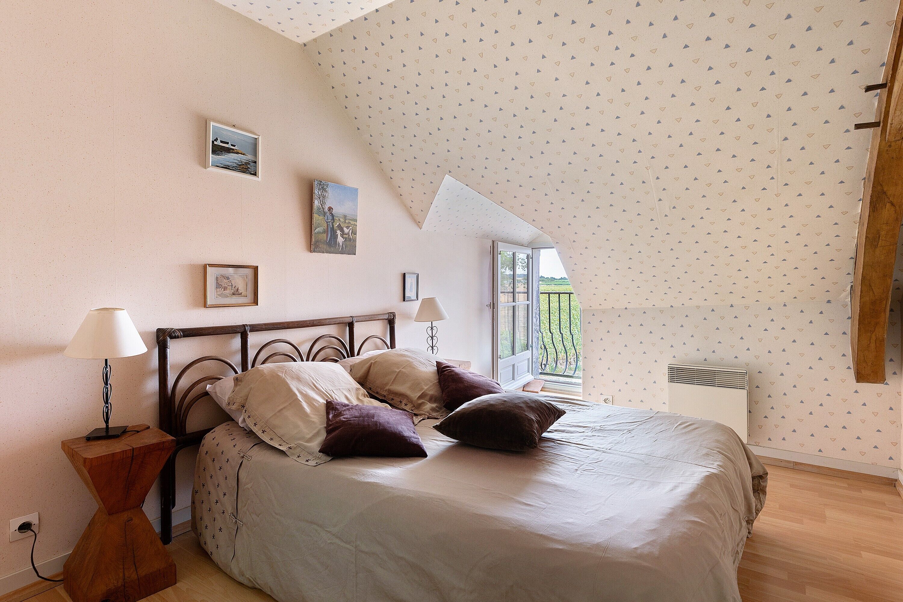 Une chambre à coucher avec un lit, des lampes de chevet, une table de chevet en bois et une fenêtre donnant sur un beau paysage.