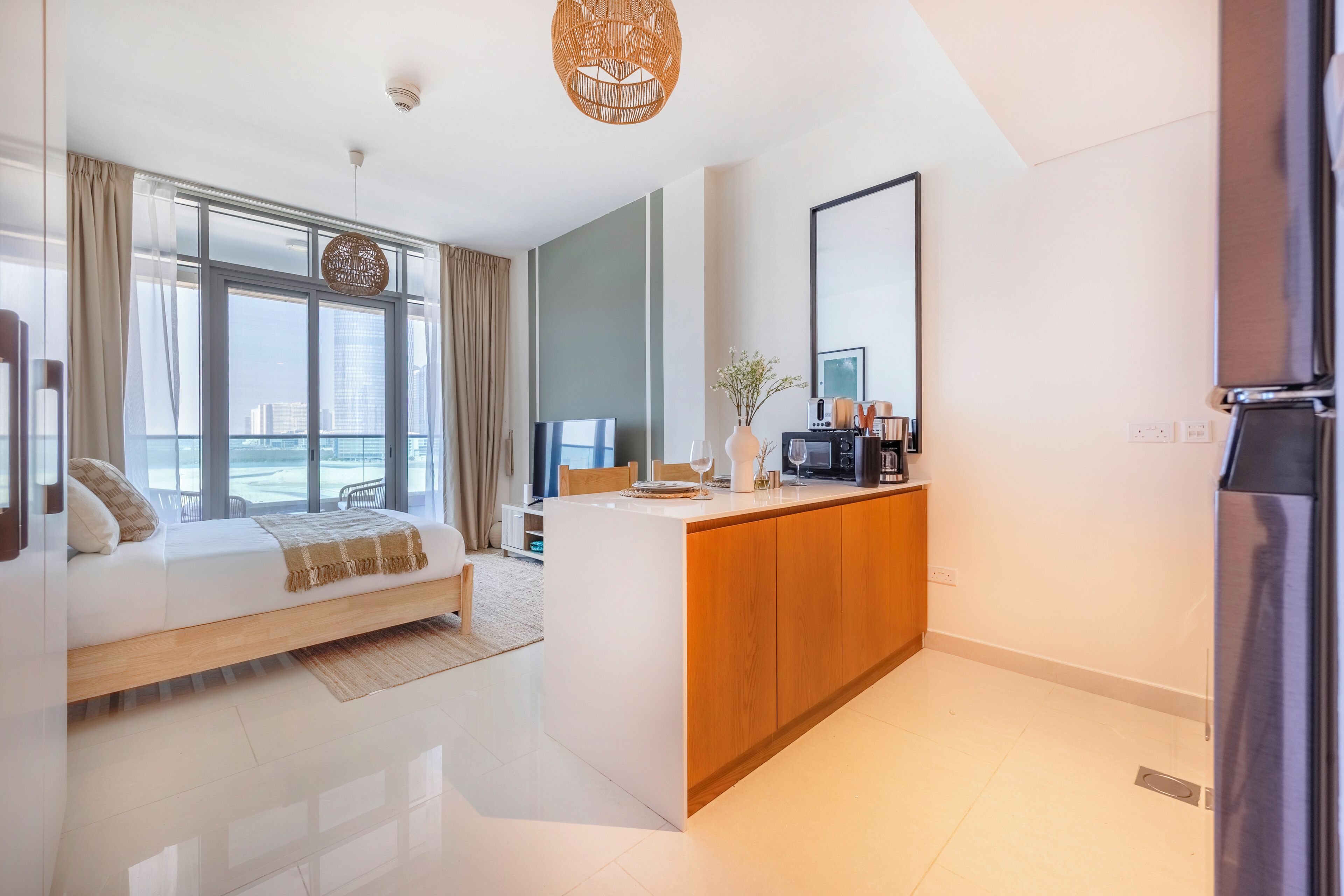 A modern hotel room with a large bed, a wooden desk, a flat-screen TV, and a view of the city.