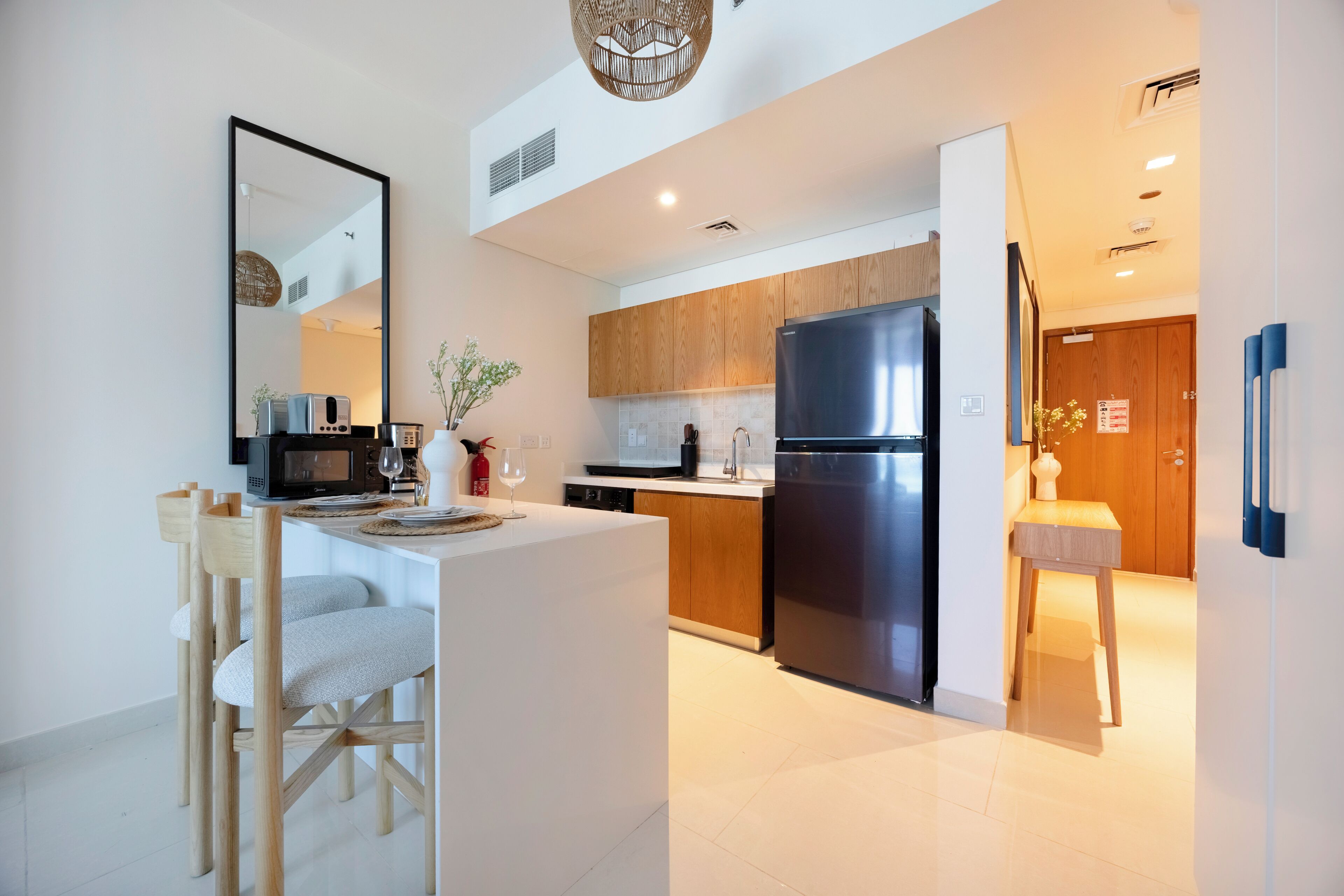 Una cocina moderna con armarios de madera, un refrigerador de acero inoxidable y una zona de comedor con sillas de madera.