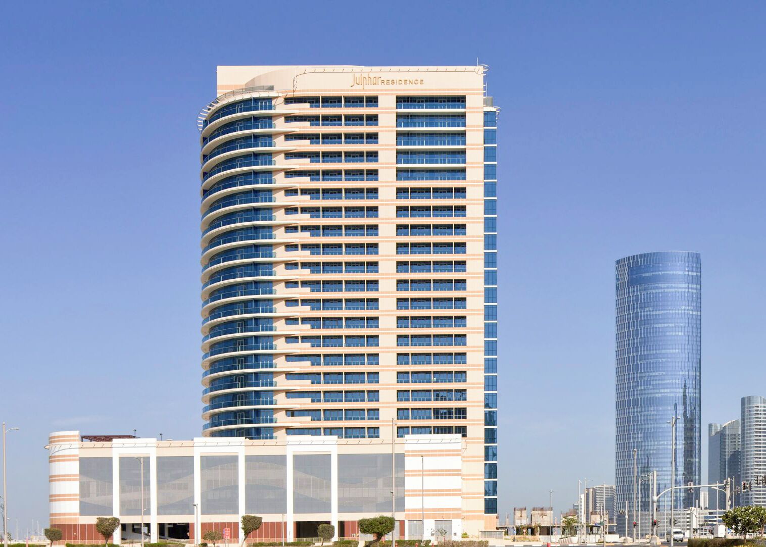 Un grand hôtel à la façade incurvée, avec de nombreux étages, et un ciel dégagé.