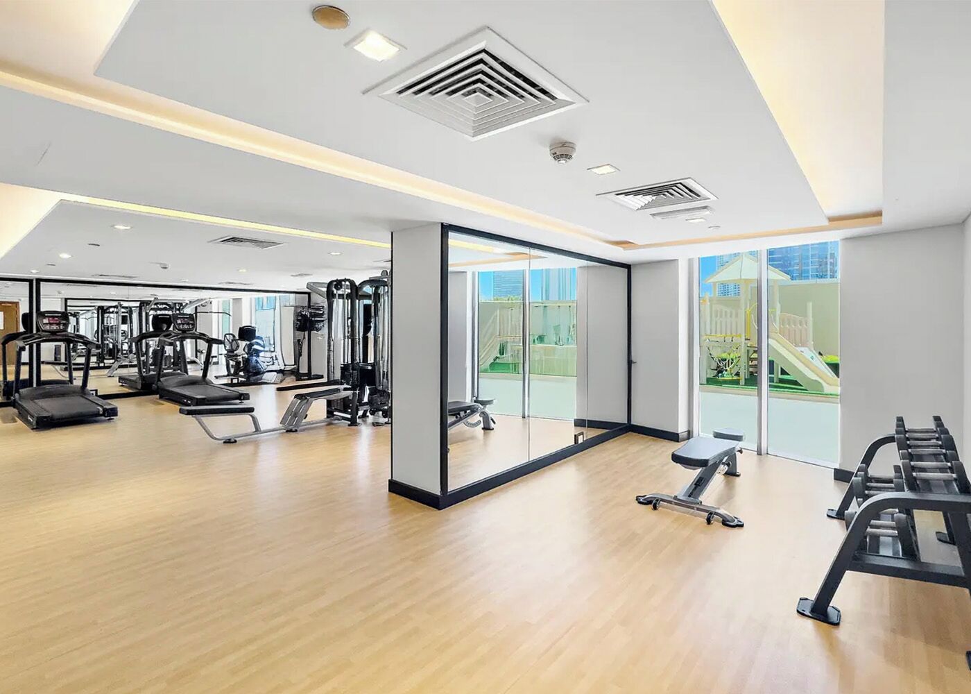 A modern gym with cardio machines, free weights, and a mirrored wall.