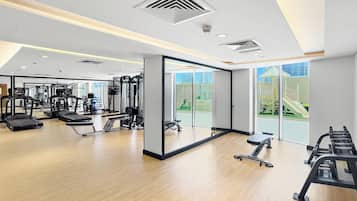 A modern gym with cardio machines, free weights, and a mirrored wall.