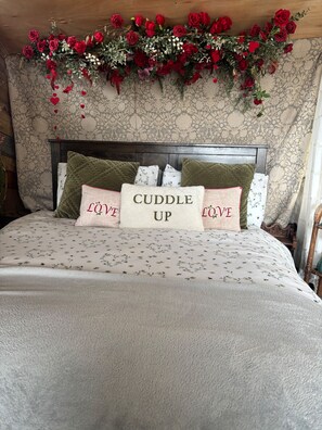 A bed with floral bedding, a headboard, and decorative pillows with the words 'Cuddle Up' and 'LOVE'. - Private Cosy Cabin With sea View Sleeps 2 (Liverpool)