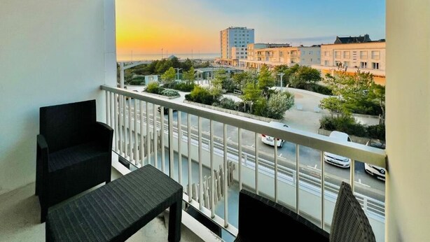 A balcony with a view of a cityscape and a sunset.