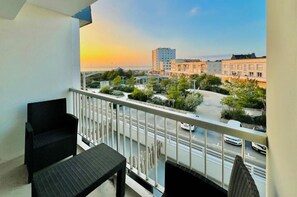 A balcony with a view of a cityscape and a sunset.