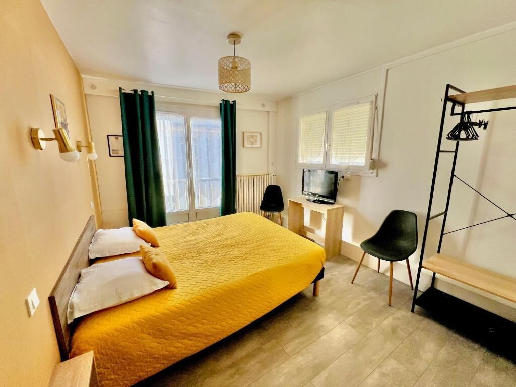 Een hotelkamer met een bed, bureau, stoel, televisie en kledingkast.