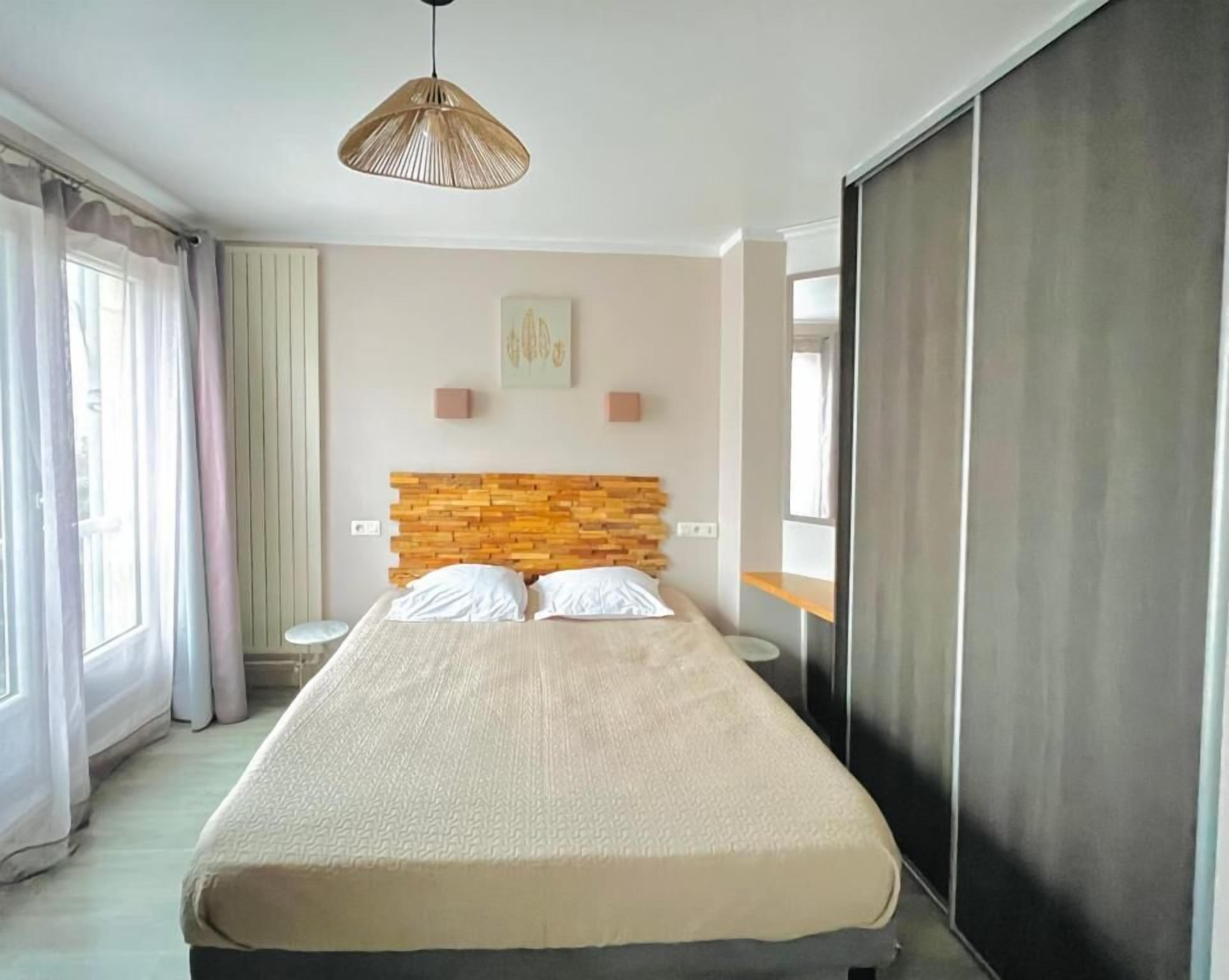 Un dormitorio moderno con una cama grande, una lámpara colgante, un cabecero de madera y una puerta corredera.