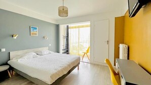 A bedroom with a bed, a desk, a chair, a television, and a window with a view.