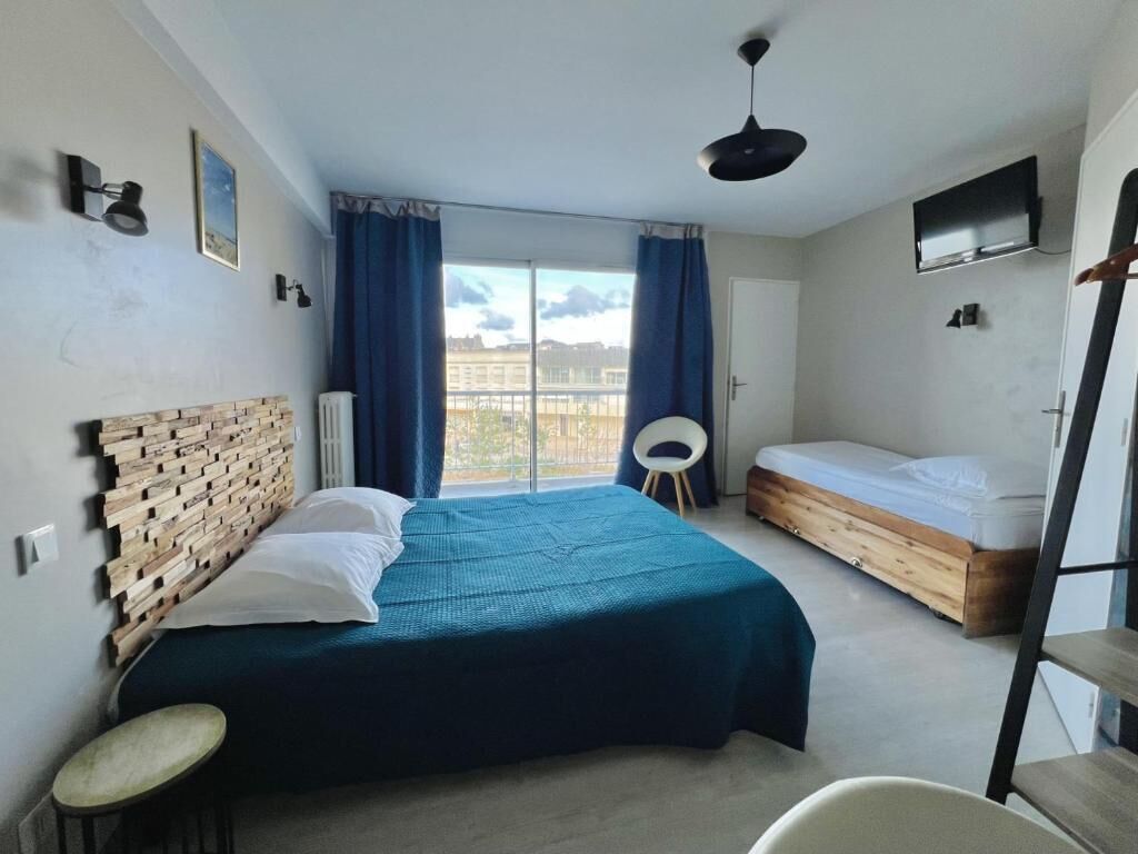 Une chambre à coucher avec un lit, une chaise, une télévision et une fenêtre avec des rideaux.
