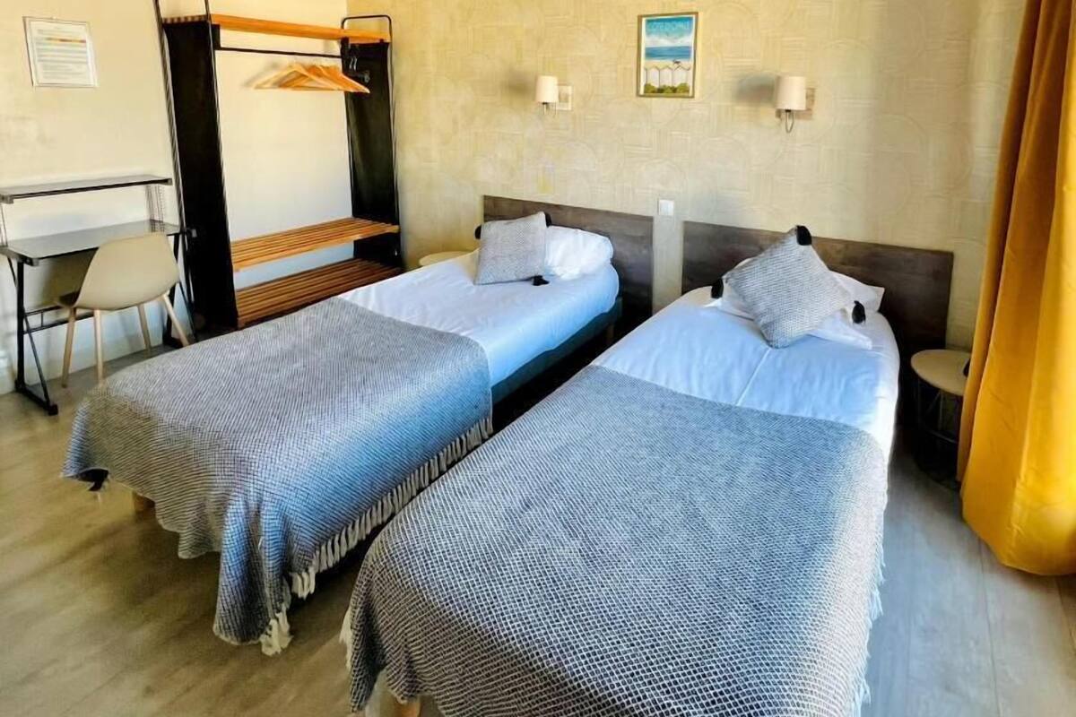 Une chambre d’hôtel avec deux lits, un bureau et un lit superposé.