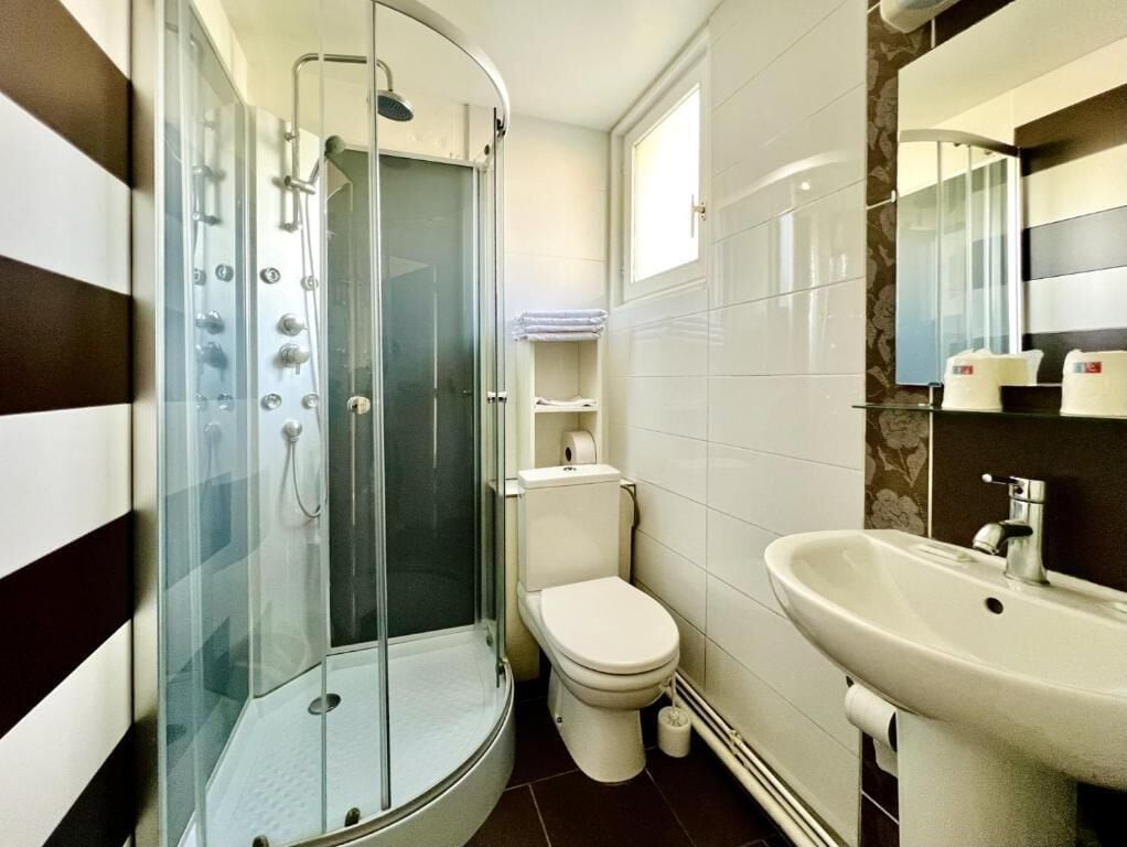 A bathroom with a glass-enclosed shower, a toilet, and a sink.
