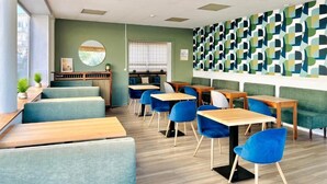 A restaurant with booths, tables, and blue chairs.