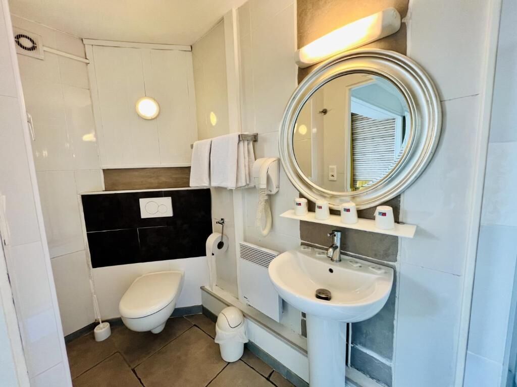 Un baño moderno con inodoro, lavabo y espejo.