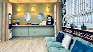 A modern kitchen with a central island, two pendant lights, a round mirror, and a built-in coffee machine.