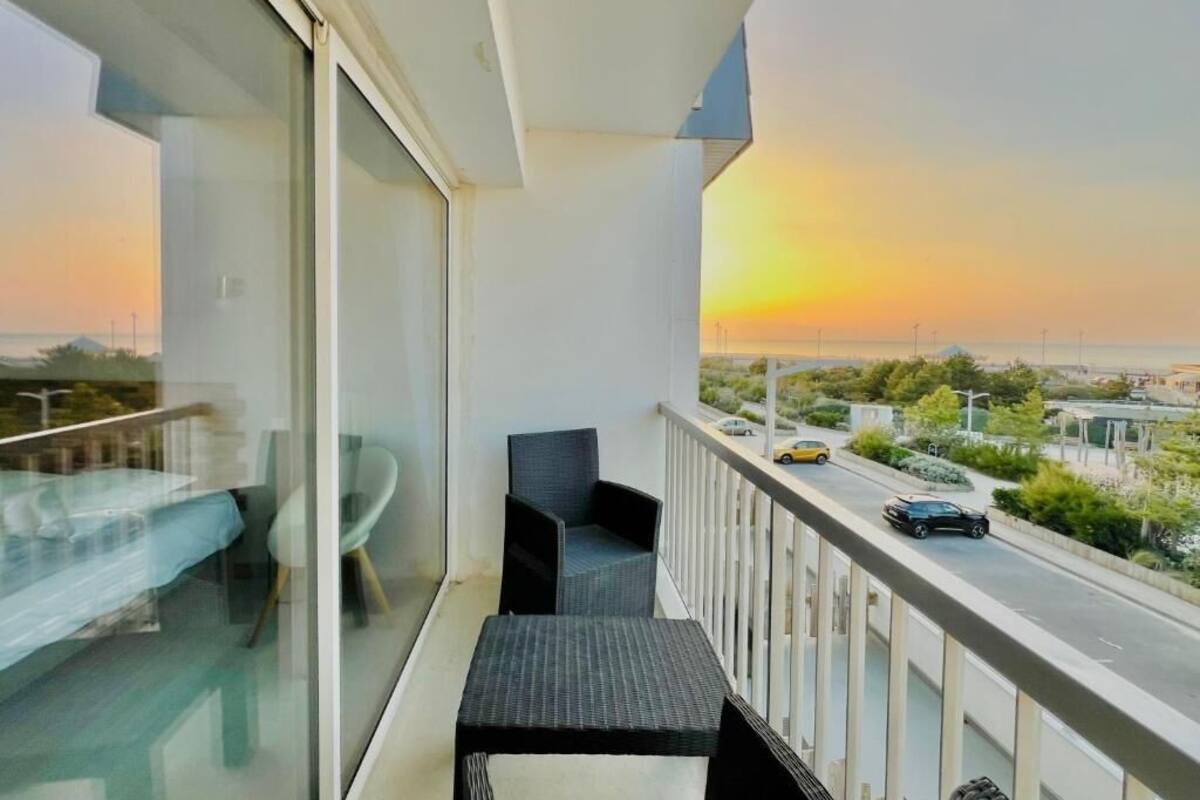 Un balcon donnant sur un coucher de soleil, une table et deux chaises.