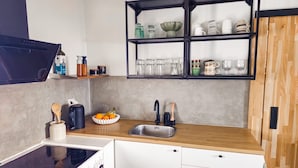 Een moderne keuken met een ingebouwde kookplaat, een spoelbak en een zwart omrande plank boven het aanrecht.