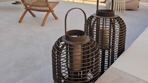 Buiten zitgedeelte met een hangmat, lounge fauteuils en twee metalen lantaarns.