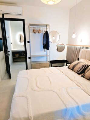 Ein Schlafzimmer mit Bett, Nachttischen, einem Kleiderschrank, einem Spiegel und einer Pendelleuchte.