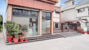 Un edificio moderno con amplios ventanales, una valla metálica y plantas en macetas.