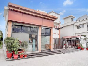 A modern building with large windows, a metal fence, and potted plants. - Deluxe Hotel Shivam Residency (Dehradun)
