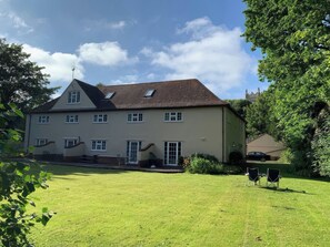 A two-story house with a sloped roof, multiple windows, and a well-maintained lawn. - No 1 The Martins (Reydon)
