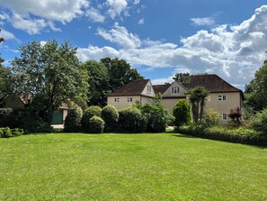A two-story house with a well-maintained lawn and surrounding greenery. - No 1 The Martins (Reydon)