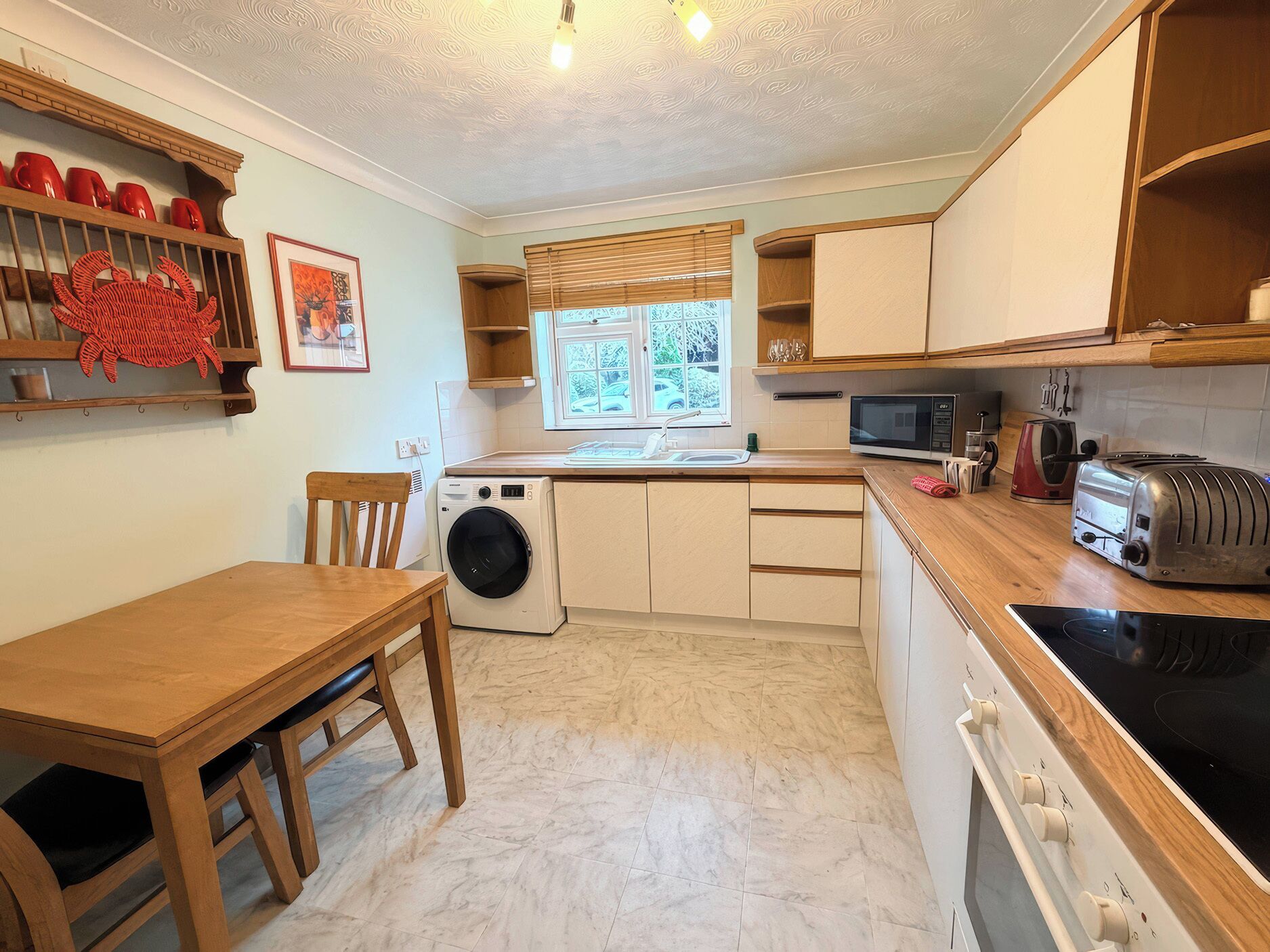 A compact kitchen with a washing machine, a microwave, a toaster, and a sink.